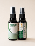 Two amber spray bottles of Terupharma pain relief medicine standing side by side against a solid beige background.